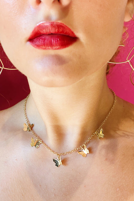 The gold butterfly colony necklace shown around a woman’s neck.