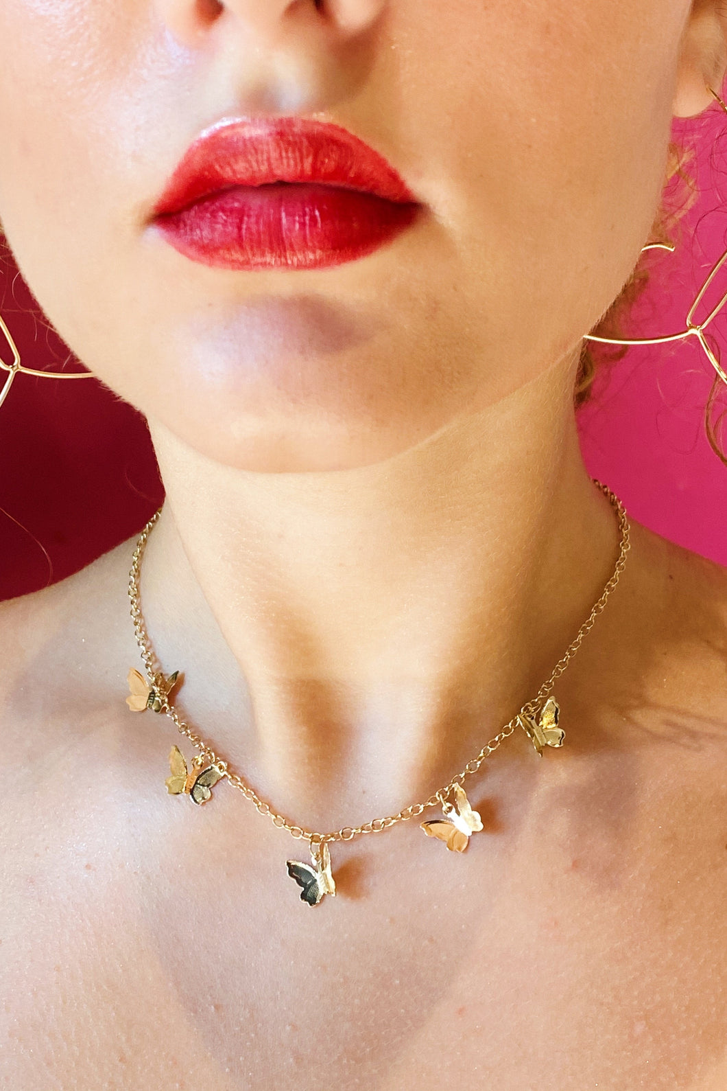 The gold butterfly colony necklace shown around a woman’s neck.
